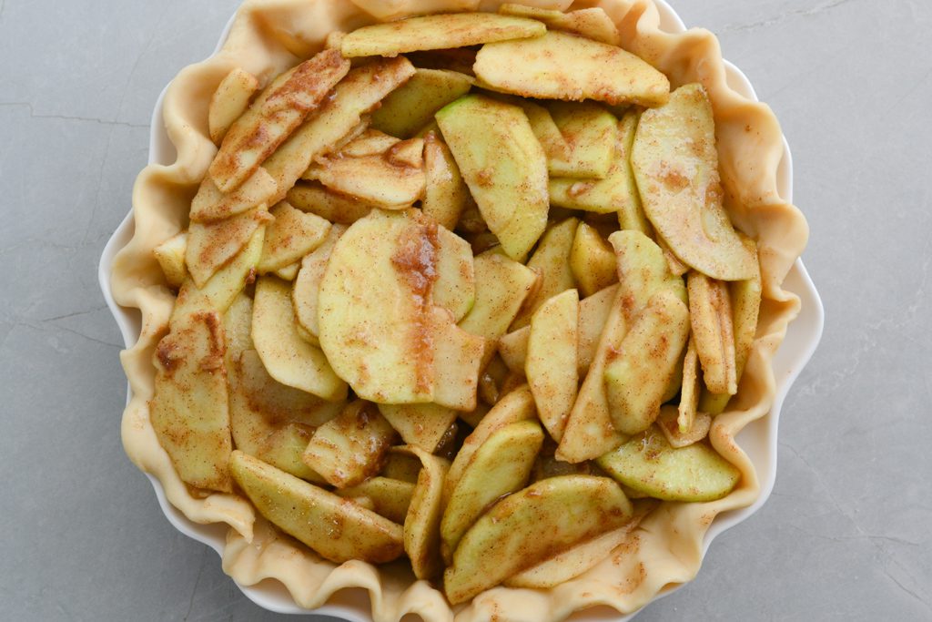 sliced apples tossed in spices in a pie pan