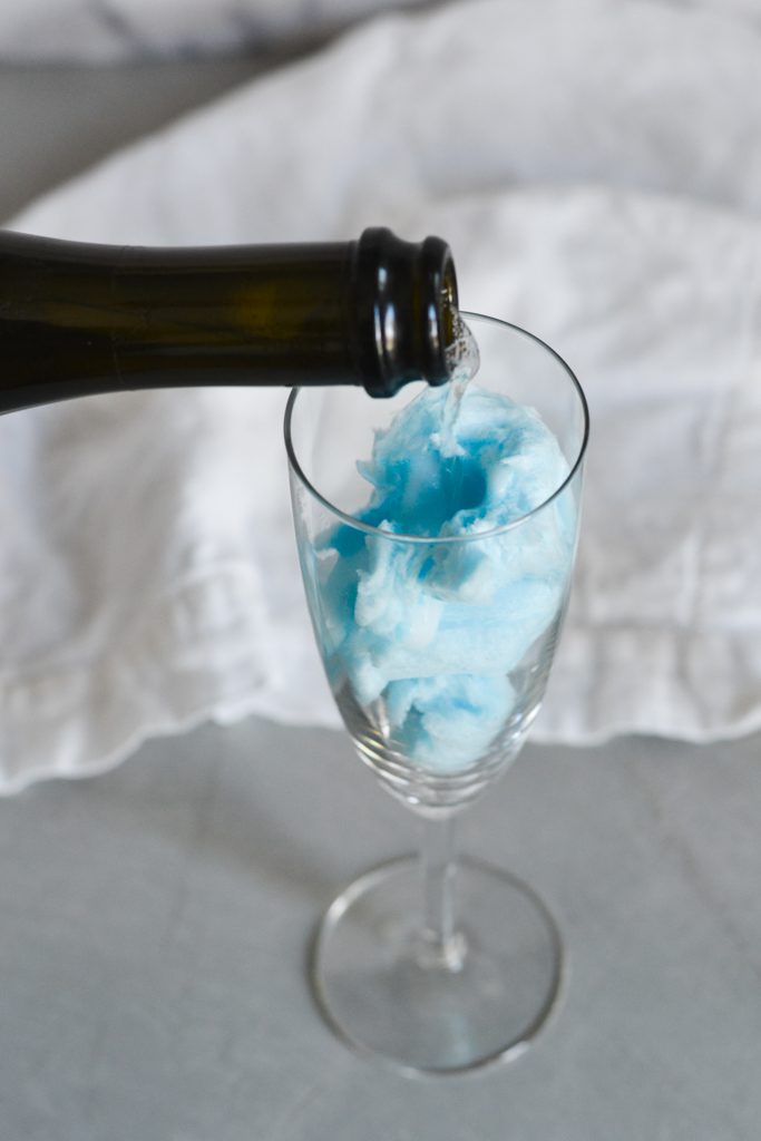 cotton candy in a glass with sparkling wine poured over the top